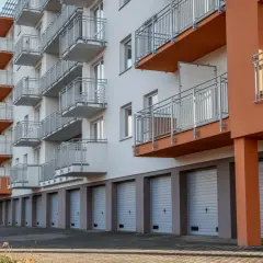 Nowoczesny budynek mieszkalny z balkonami i garażami podziemnymi.