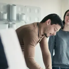 Para młodych omawia warunki, jak wygląda wynajem mieszkania. Mężczyzna pochyla się nad dokumentami, kobieta uśmiecha się.