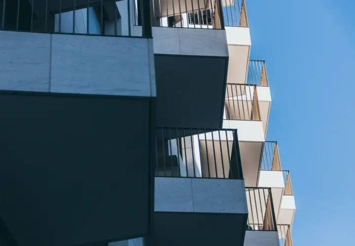 Nowoczesne balkony z metalowymi balustradami na tle błękitnego nieba.