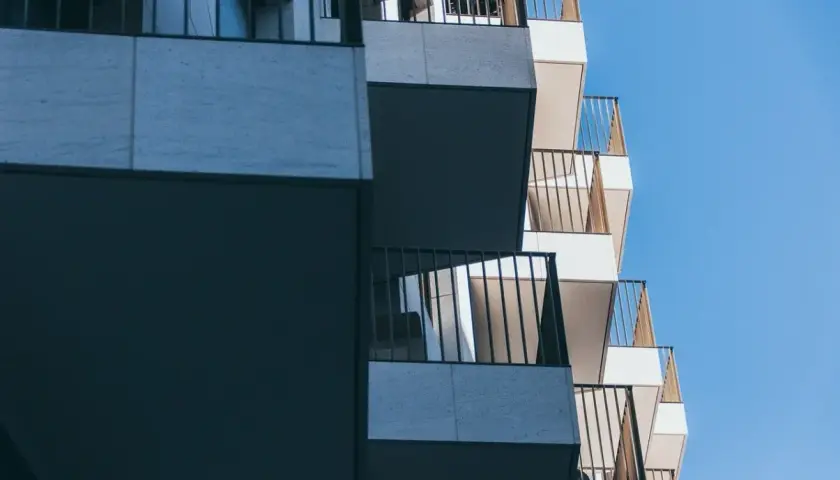 Nowoczesne balkony z metalowymi balustradami na tle błękitnego nieba.
