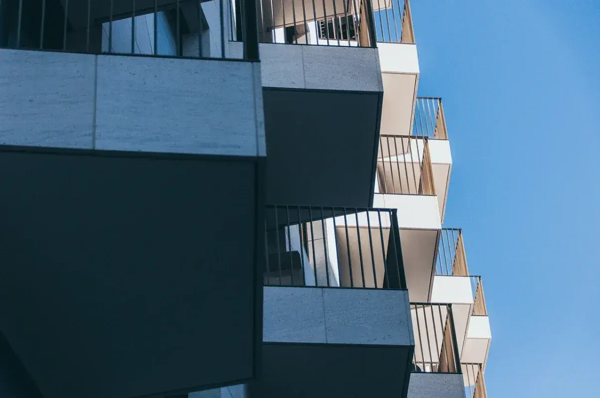 Nowoczesne balkony z metalowymi balustradami na tle błękitnego nieba.