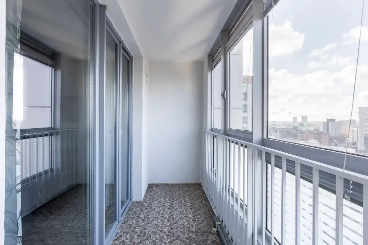 Przykładowe wnętrze balkonu w bloku, idealne do rozważenia, jak zabudować balkon w bloku, z widokiem na miasto.